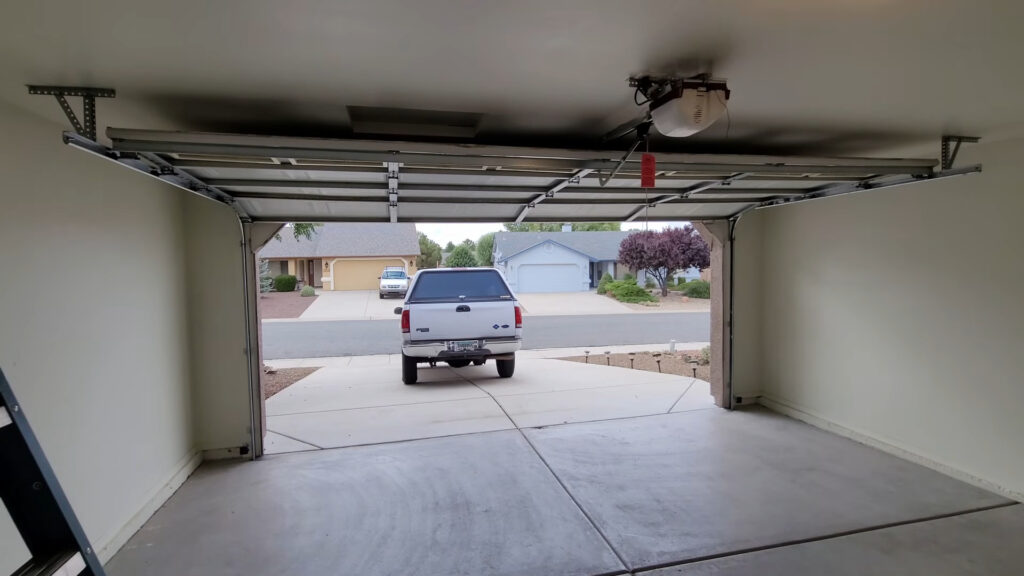 Open garage door seen from inside, showing the opener rail, horizontal tracks and red emergency release cord